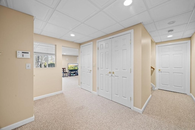 corridor with carpet floors and a drop ceiling