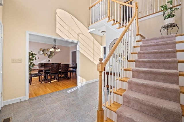 stairs featuring an inviting chandelier, a towering ceiling, and wood-type flooring