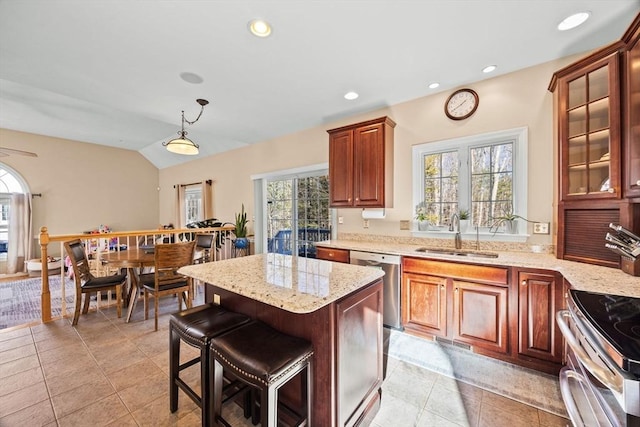 kitchen featuring lofted ceiling, sink, appliances with stainless steel finishes, a kitchen island, and decorative light fixtures