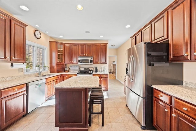 kitchen featuring a kitchen bar, sink, a center island, light tile patterned floors, and appliances with stainless steel finishes