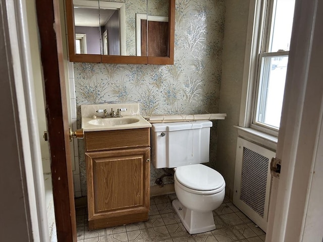 bathroom with vanity, radiator, and toilet