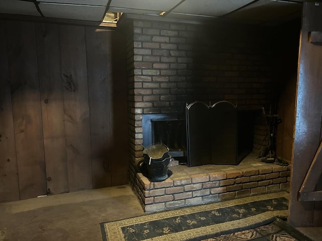 room details featuring a brick fireplace, a paneled ceiling, and wooden walls