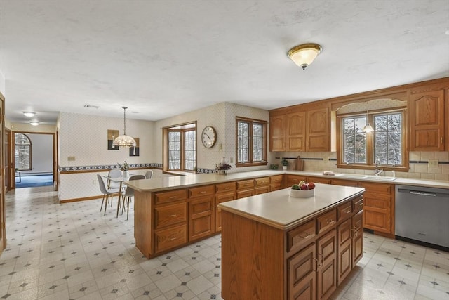 kitchen with sink, a notable chandelier, dishwasher, a kitchen island, and hanging light fixtures