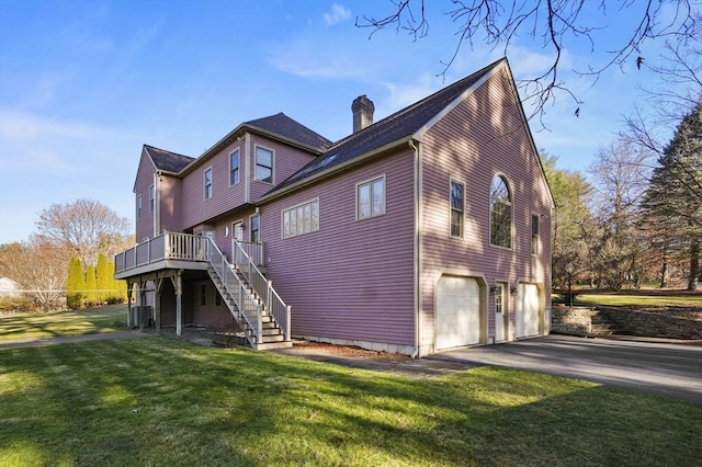 view of property exterior with a garage, a lawn, and a wooden deck