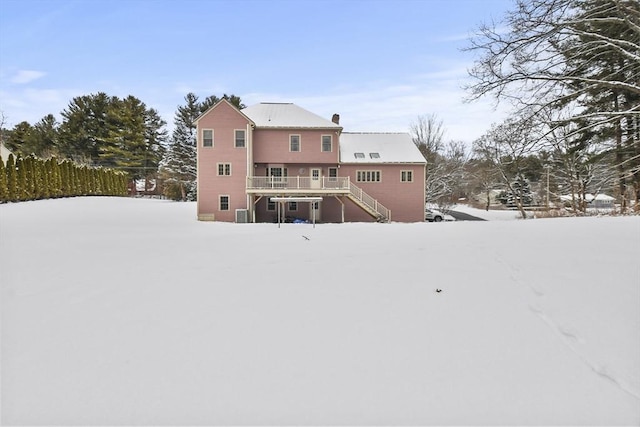 snow covered rear of property with a wooden deck