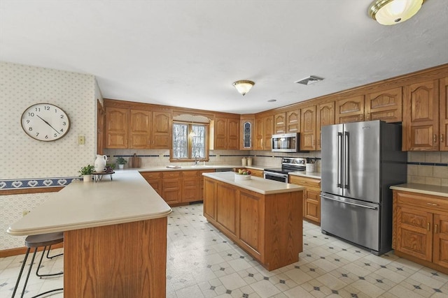 kitchen featuring a kitchen bar, sink, a center island, stainless steel appliances, and decorative backsplash