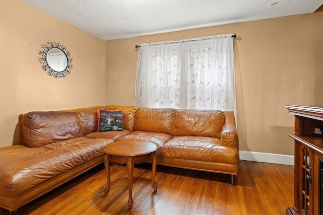 living area with hardwood / wood-style floors, baseboards, and a textured ceiling