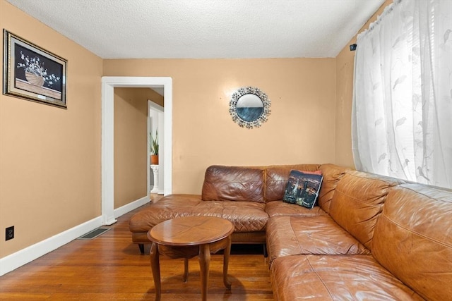 living area with wood finished floors, baseboards, and a textured ceiling