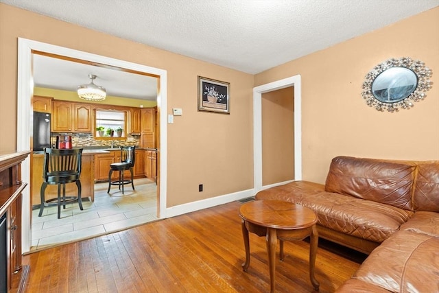 living area with light wood-style flooring, baseboards, and a textured ceiling