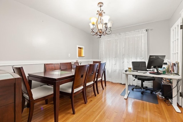 dining space with a chandelier, light wood finished floors, and an office area
