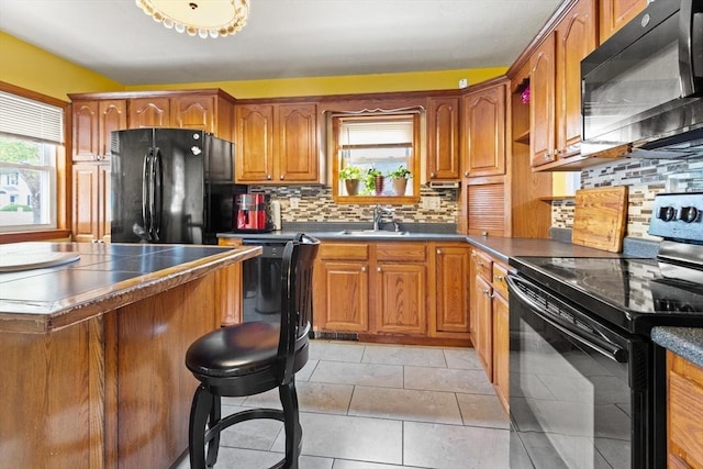 kitchen featuring black appliances, plenty of natural light, brown cabinets, and backsplash