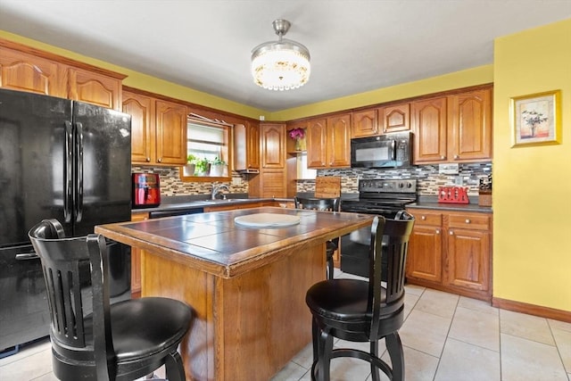 kitchen with black appliances, a breakfast bar area, dark countertops, and decorative backsplash