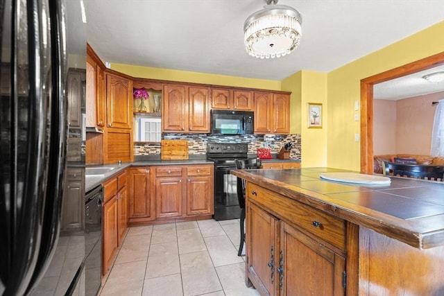 kitchen with black appliances, brown cabinets, tasteful backsplash, and light tile patterned floors