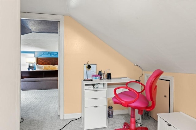 carpeted office with vaulted ceiling and baseboards