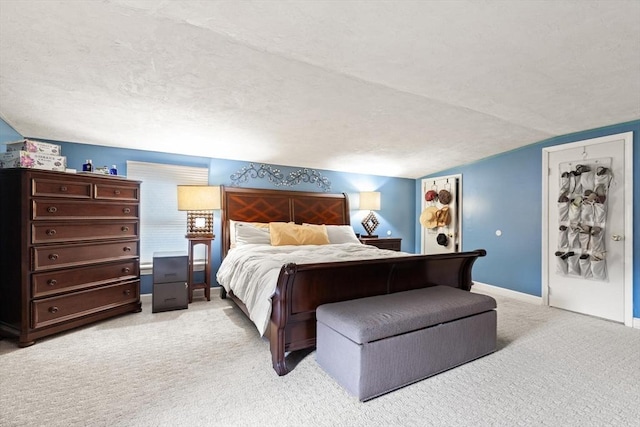 bedroom featuring light colored carpet, baseboards, and a textured ceiling