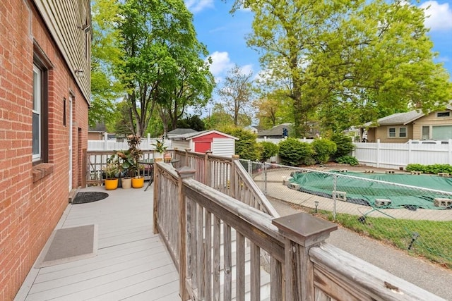 wooden deck with a fenced backyard, an outbuilding, and a shed