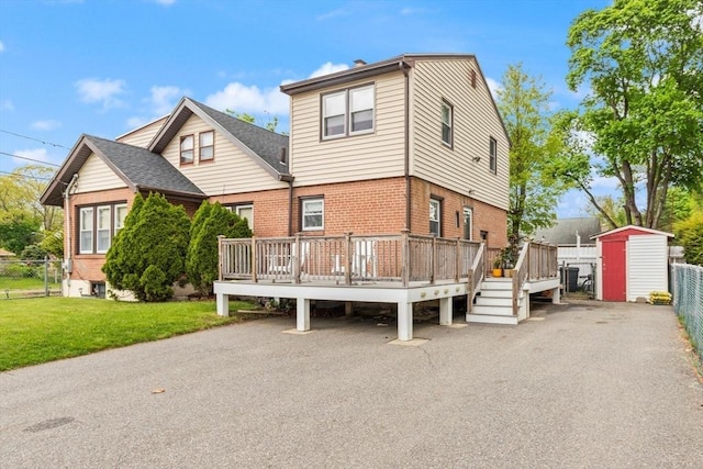 view of front of home featuring a storage shed, brick siding, a wooden deck, and an outdoor structure