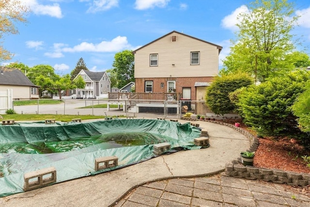 view of swimming pool with a wooden deck, a covered pool, a residential view, and fence