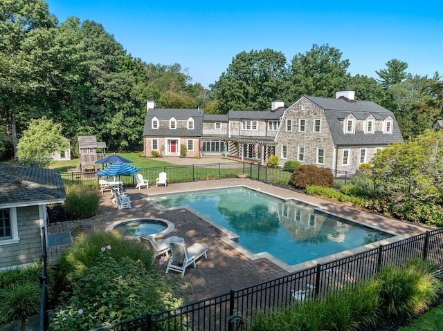 rear view of house featuring a pool with hot tub, an outbuilding, and a patio