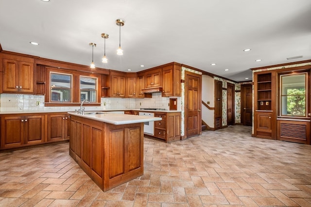 kitchen featuring hanging light fixtures, a kitchen island, decorative backsplash, and sink