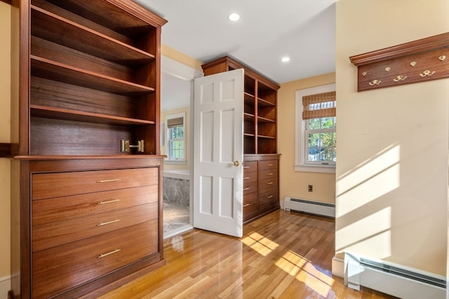 spacious closet with a baseboard heating unit and light hardwood / wood-style flooring