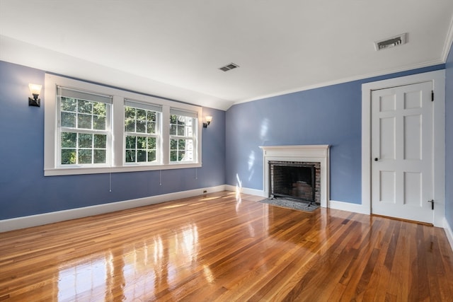 unfurnished living room with ornamental molding, a brick fireplace, and wood-type flooring