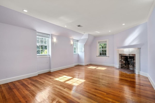 unfurnished living room featuring baseboards, visible vents, wood finished floors, a fireplace, and recessed lighting