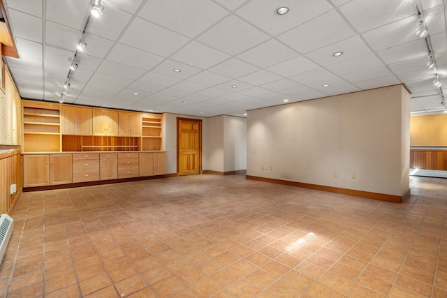 tiled empty room featuring rail lighting and a baseboard radiator