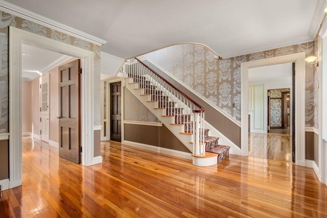 interior space with wallpapered walls, wood-type flooring, stairs, and crown molding