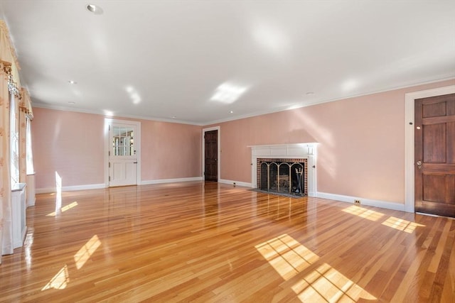 unfurnished living room with ornamental molding, a brick fireplace, baseboards, and light wood finished floors