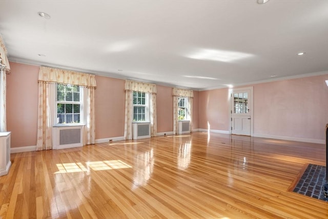 unfurnished living room featuring baseboards, crown molding, and light wood finished floors