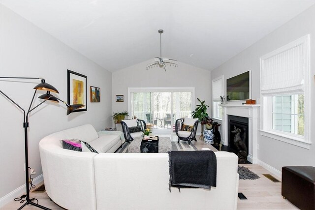34 Split Rock Ln, Mattapoisett, MA 02739 - living area featuring light wood-style floors, lofted ceiling, a chandelier, a glass covered fireplace, and baseboards