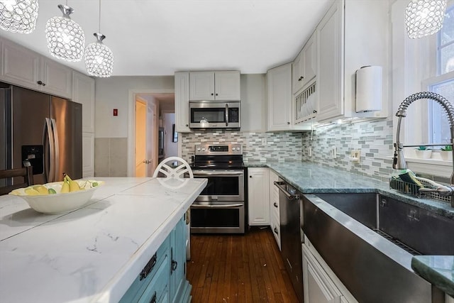 kitchen featuring white cabinetry, decorative backsplash, sink, decorative light fixtures, and stainless steel appliances