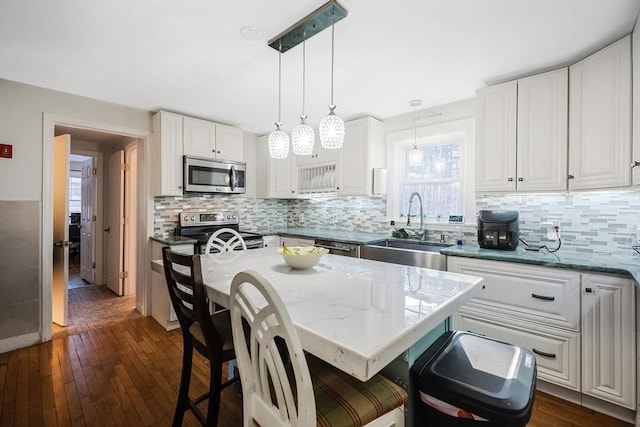 kitchen with a kitchen island, sink, white cabinetry, and appliances with stainless steel finishes