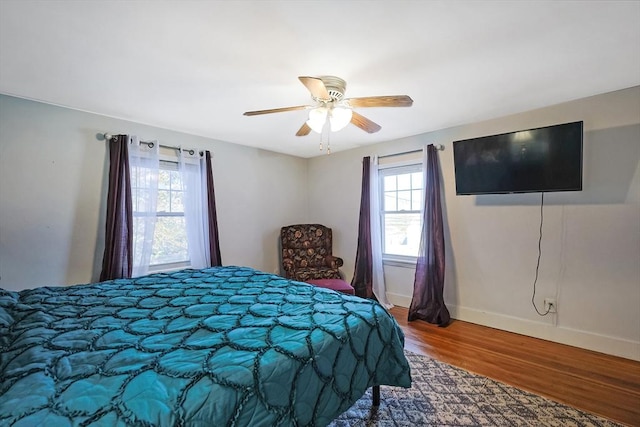 bedroom with ceiling fan, multiple windows, and wood-type flooring