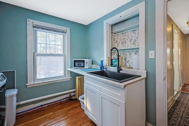 kitchen with sink, hardwood / wood-style floors, and white cabinets