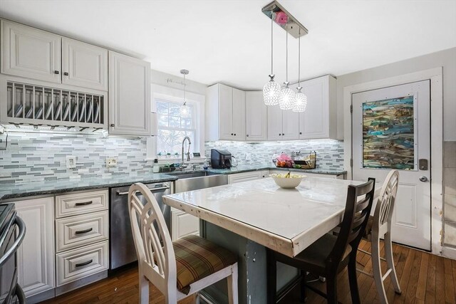 kitchen with a kitchen breakfast bar, stainless steel dishwasher, hanging light fixtures, white cabinets, and a kitchen island