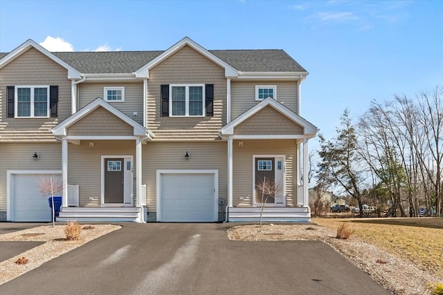 townhome / multi-family property featuring driveway, roof with shingles, and an attached garage