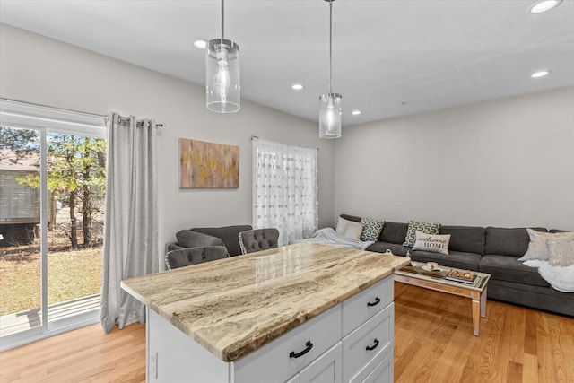 kitchen featuring white cabinets, pendant lighting, open floor plan, and light wood-type flooring