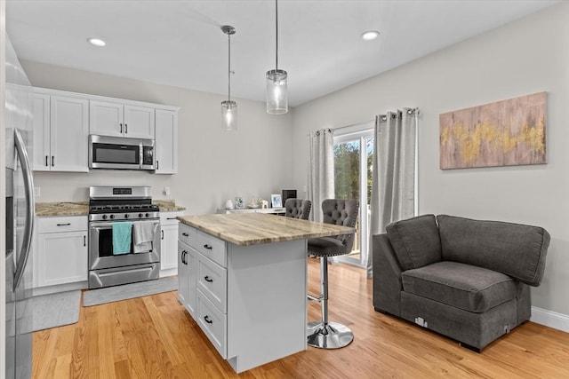 kitchen featuring a kitchen breakfast bar, light wood-style floors, appliances with stainless steel finishes, and white cabinetry