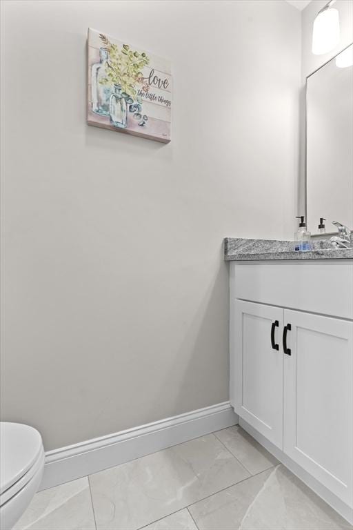 bathroom featuring vanity, toilet, baseboards, and marble finish floor