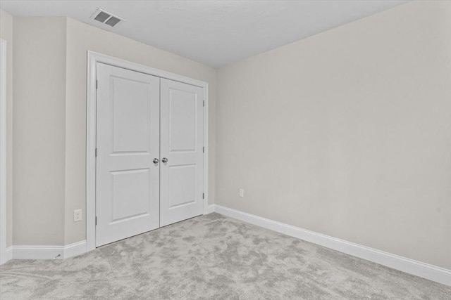 unfurnished bedroom with a closet, visible vents, carpet flooring, and baseboards