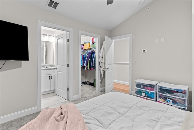 bedroom featuring visible vents, a walk in closet, ensuite bathroom, a closet, and vaulted ceiling