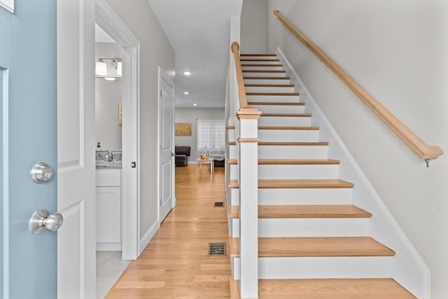 stairs with recessed lighting, visible vents, and wood finished floors