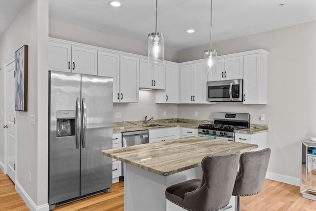 kitchen with light wood-style flooring, white cabinetry, stainless steel appliances, and light stone countertops