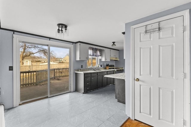 kitchen featuring sink, white gas range oven, and gray cabinetry