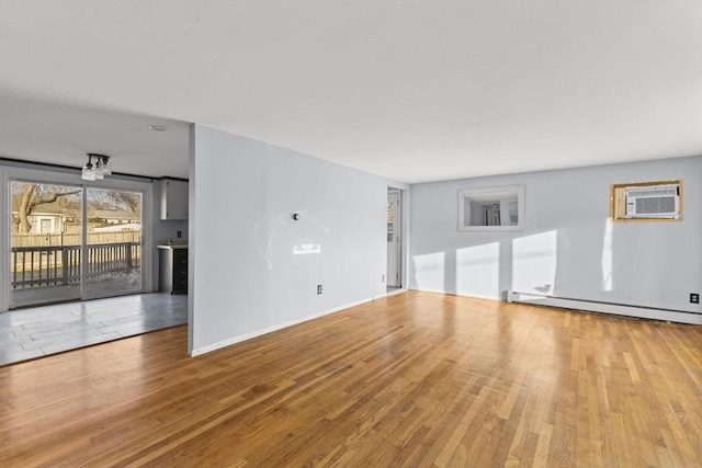 unfurnished living room with light hardwood / wood-style floors, a wall mounted AC, and a baseboard radiator