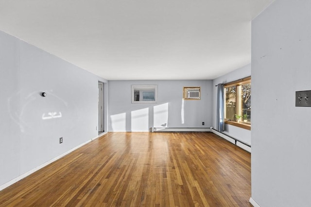 unfurnished living room with baseboard heating, hardwood / wood-style floors, and a wall mounted AC