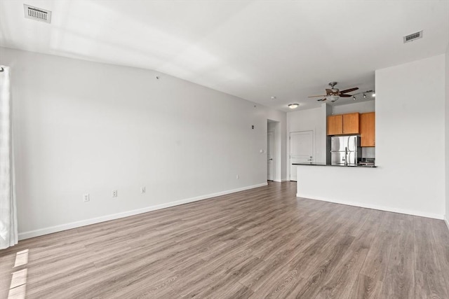 unfurnished living room with visible vents, light wood-style flooring, ceiling fan, and baseboards