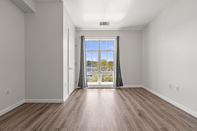 empty room with visible vents, baseboards, and wood finished floors